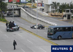 Policías y un autobús bloquean una autovía que conduce al lugar donde se encontraron los cadáveres en Boca del Rio