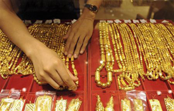 Una vendedora coloca collares de oro en un muestrario