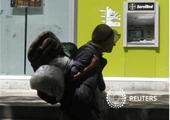 Una mujer sin hogar pasa junto a una sucursal de Bankia en Madrid, el 12 de junio de 2012