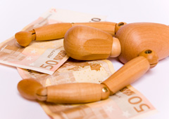 Un muñeco de madera tumbado sobre billetes de cincuenta euros