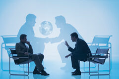 Negociando que es gerundio Dos personas sentadas negociando