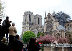 Transeúntes toman fotografías de la catedral de Notre-Dame en París después del incendio que destruyó partes de la estructura gótica. April 16, 2019