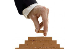 Hoy entra en vigor la reforma laboral Una mano poniendo un ladrillo.