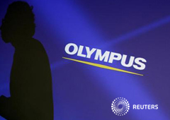 Imagen de un empleado de la empresa cuya silueta aparece reflejada en una pantalla con el logo de Olympus anes de una rueda de prensa en Tokio el 13 de febrero.