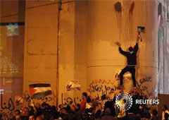 Palestinos toman parte en una manifestación mientras otro escala por el muro israelí de la controversía en la ciudad cisjordana de Belén, el 29 de noviembre de 2012