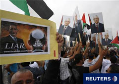 Un palestino sostiene una pancarta con uan caricatura de Obama en Ramala