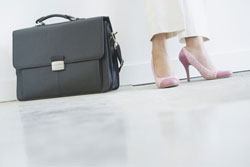 Los pies de una mujer con un maletín alado