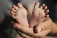 Exención de la prestación por maternidad Unos pies de bebe sobre una mano