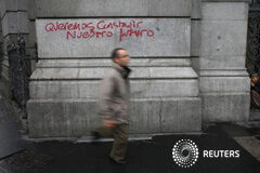 Uno de cada cinco españoles, bajo el umbral de riesgo de pobreza Una mujer pide dinero junto a un grafiti que dice "queremos construir nuestro futuro" en el centro de Madrid