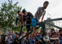 Varios inmigrantes saltan una valla durante enfrentamientos con la policía húngara en Roszke el 16 de septiembre de 2015