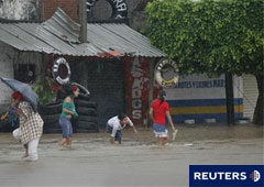 Residentes cruzan una calle inundada por las intensas lluvias