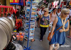 Unos turistas caminan junto a una tienda de recuerdos con paellas en exposición, en Valencia el 17 de agosto de 2017. REUTERS/Heino Kalis