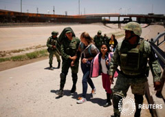 Miembros de la Guardia Nacional de México escoltan a una mujer de Nicaragua y a su hija luego de detenerlas cuando intentaban cruzar ilegalmente la frontera entre Estados Unidos y México, en Ciudad Juárez, México. 21 de junio, 2019.