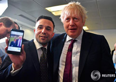 El primer ministro de Reino Unido, Boris Johnson, muestra una fotografía en el teléfono de un simpatizante que posa para una foto mucho antes en el Centro de Llamadas de la Sede de la Campaña Conservadora en el centro de Londres, Reino Unido, el 8 de dici