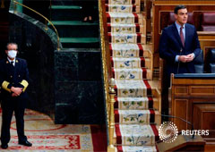 Un ujier del Congreso de los Diputados en Madrid, de pie y con una mascarilla cerca del presidente del Gobierno español, Pedro Sánchez, durante el debate para solicitar una cuarta prórroga del estado de alarma para frenar el coronavirus, el 6 de mayo de 2