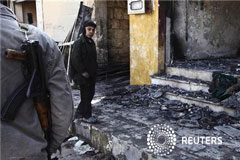 El Ejército gana terreno en el aniversario de la revuelta siria Un miembro del Ejército Libre de Siria junto a un niño cerca de una tienda destruida por los bombardeos gubernamentles en Idlib