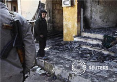 Un miembro del Ejército Libre de Siria junto a un niño cerca de una tienda destruida por los bombardeos gubernamentles en Idlib