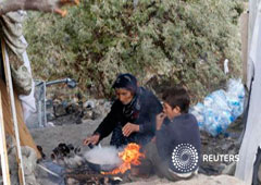 Unos refugiados sirios se sientan alrededor de un fuego mientras cocinan frente a una tienda en Ankara, el 5 de octubre de 2013