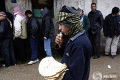 La ONU condena a Damasco, que sigue su ofensiva un niño come pan mientras varias personas esperan junto a una panadería en Al Qusayr, una ciudad del oeste de Siria