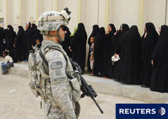 Un soldado estadounidense cerca de unas mujeres que hacen cola para recoger ayuda en Bagdad, el 27 de septiembre de 2010.