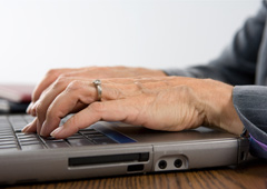 Una persona mayor tecleando en un ordenador portátil