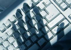 El teclado de un ordenador y sobre él la sombra de una mano