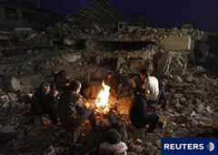 Unos hombres sentados ante un fuego entre las ruinas de un edificio derrumbado en Ercis, cerca de la capital provincial, Van, en el sureste del país.