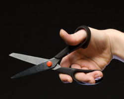 Una mano cortando con unas tijeras.