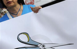 Admiten el recurso contra el recorte salarial a los funcionarios una profesora con un cartel que simboliza los recortes al sector público durante una protesta en Oviedo el 30 de junio de 2010.