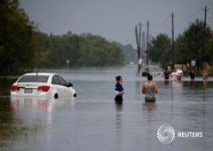 Residentes camina en una zona inundada en Harvey, Houston, el 27 de agosto de 2017