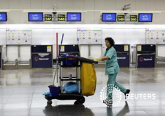 un limpiadora pasa por delante de los mostradores de la aerolínea Spanair en el aeropuerto de Madrid Barajas, el 29 de enero de 2012