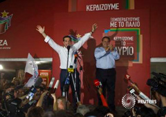 Tsipras levanta los brazos mientras que su socio y líder del partido Griegos Independientes, Panos Kammenos (a la derecha) aplaude en el podio tras gannr las elecciones en Atenas el 20 de septiembre de 2015