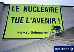 Un ciclista junto a un cartel en el que puede leerse en francés 
