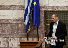 El ministro de finanzas griego Yanis Varoufakis pasa delante de una bandera de la UE y otra griega durante una sesión parlamentaria en Atenas, 2 de abril de 2015