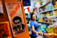 Venezuela cumple con primer vencimiento de deuda del 2015, promete seguir pagando Se ve una imagen de Nicolás Maduro y la palabra "devaluado" en un mercado de Caracas el 13 de febrero de 2015