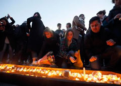 Varias personas encienden velas y depositan flores en una vigilia en Trafalgar Square el 23 de marzo
