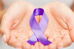 Concurso de normas en los delitos de violencia de género manos de una mujer sujetando un lazo morado