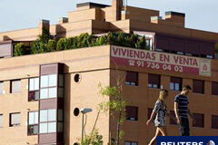 El capital prestado para la compra de viviendas baja en junio Una pareja pasa ante un bloque de viviendas en venta en Madrid.
