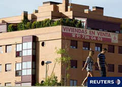 Una pareja pasa ante un bloque de viviendas en venta en Madrid.