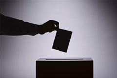 17 Colegios de Abogados celebran elecciones en noviembre y diciembre Una mano con una papeleta y una urna