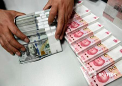Un empleado de banca contando yuanes y dólares en una sucursal del Bank of China en Taiyuan, en la provincia china de Shanxi, el 4 de enero de 2016
