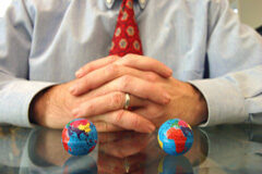 La internacionalización de los despachos de abogados Un abogado sentado con dos bolas del mundo pequeñas