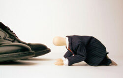 Sobre el mal de altura Un muñeco de abogado de rodillas sobre los zapatos de un ejecutivo.