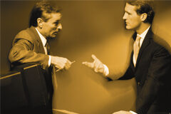 Solución de conflictos: una oportunidad para mejorar el clima de la organizaciones Dos personas hablando en una oficina y una de ellas apollada en la pantalla del ordenador