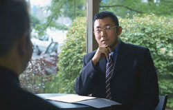 Headhunting para profesionales colegiados: definición y destinatarios Un señor trajeado entrevistando a otro con gesto serio