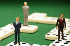 El valor de obtener la certificación ISO 9001:2008 Unos muñecos sobre unas piezas de dominó.