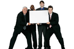 El Marketing como Herramienta de Motivación Cuatro hombres de traje sosteniendo entre todos una cartulina.