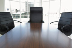 Tipos de management en los despachos de abogados Una mesa de reuiones vacía con tres sillas y al fondo se ves edificios