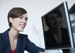 Una mujer reflejando su cara en la pantalla de un ordenador.