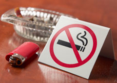 Un cenicero, un mechero y un cartel de prohibido fumar.
